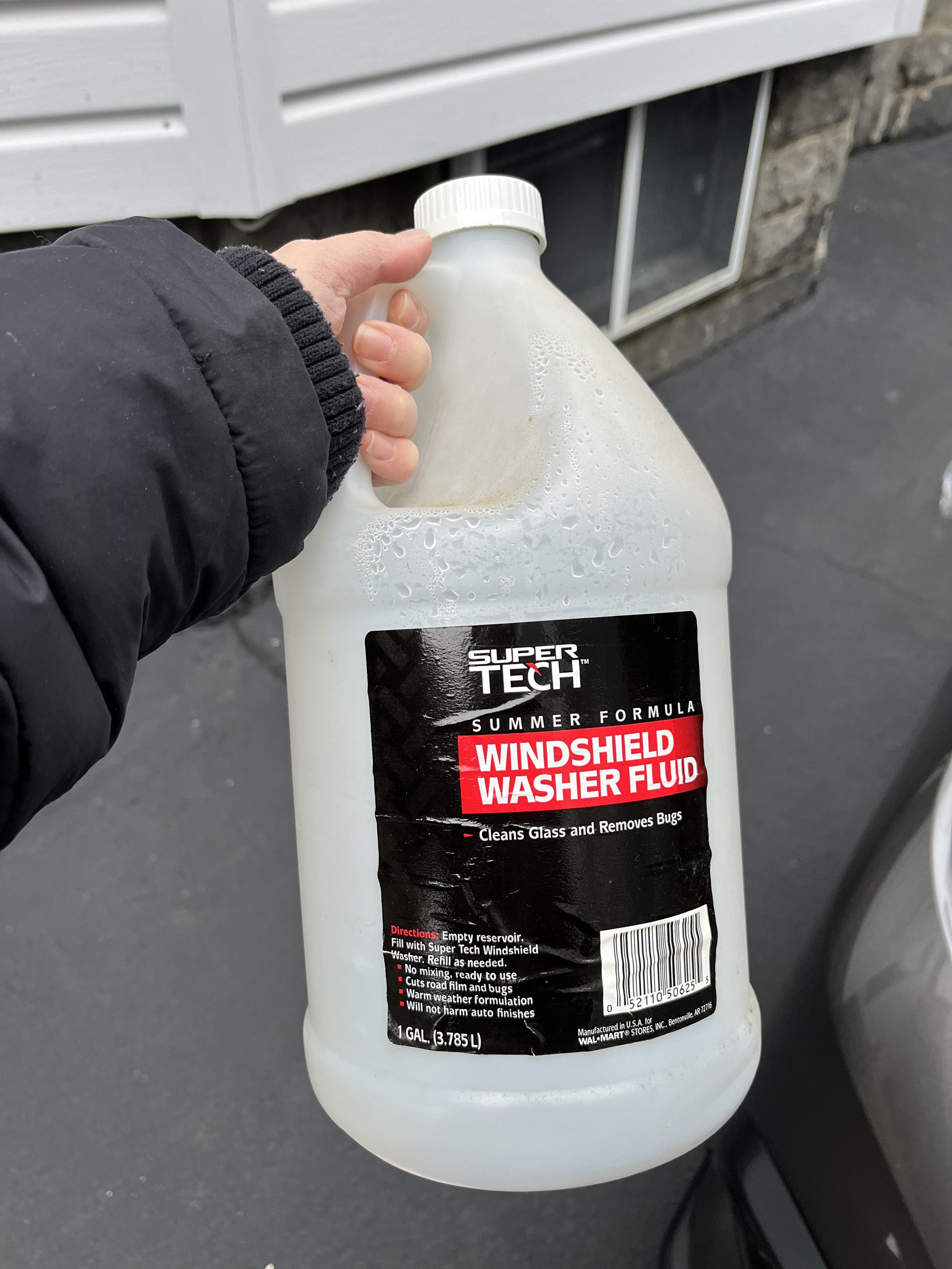 Hand holding a Super Tech Summer Formula windshield washer fluid jug