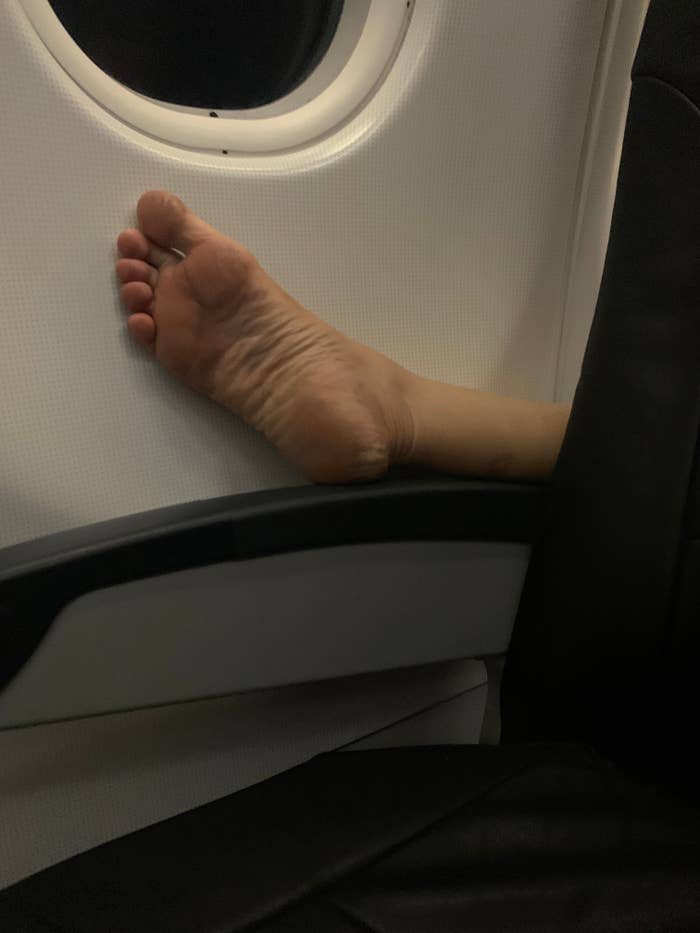 Bare foot protruding over armrest edge on an airplane