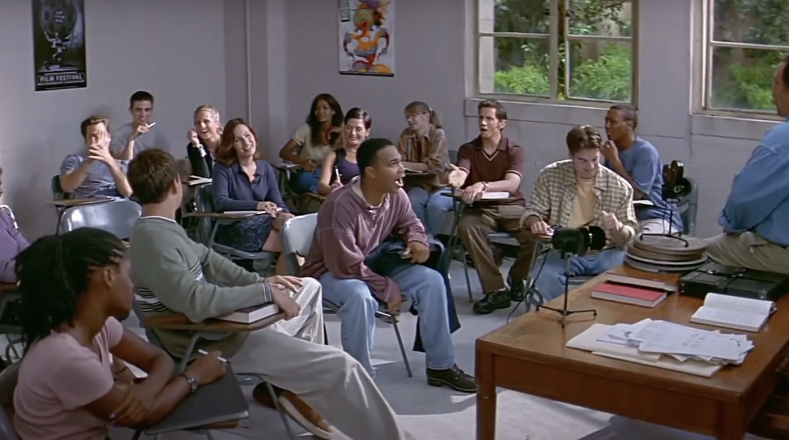 A classroom scene with students sitting at desks, focusing attentively on a person standing at the front