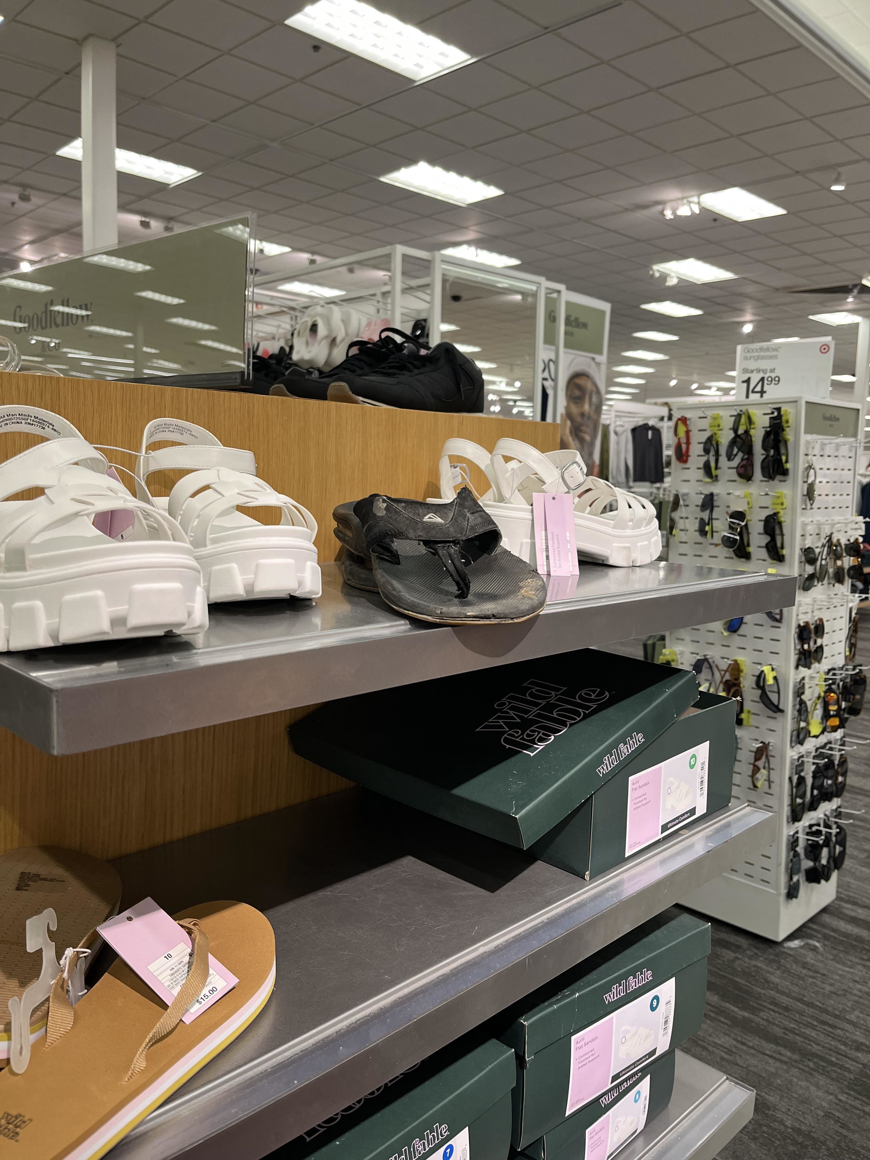 Shelves stocked with various shoes and shoeboxes in a retail store setting and one person&#x27;s used dirty flop-flop sitting on the shelf