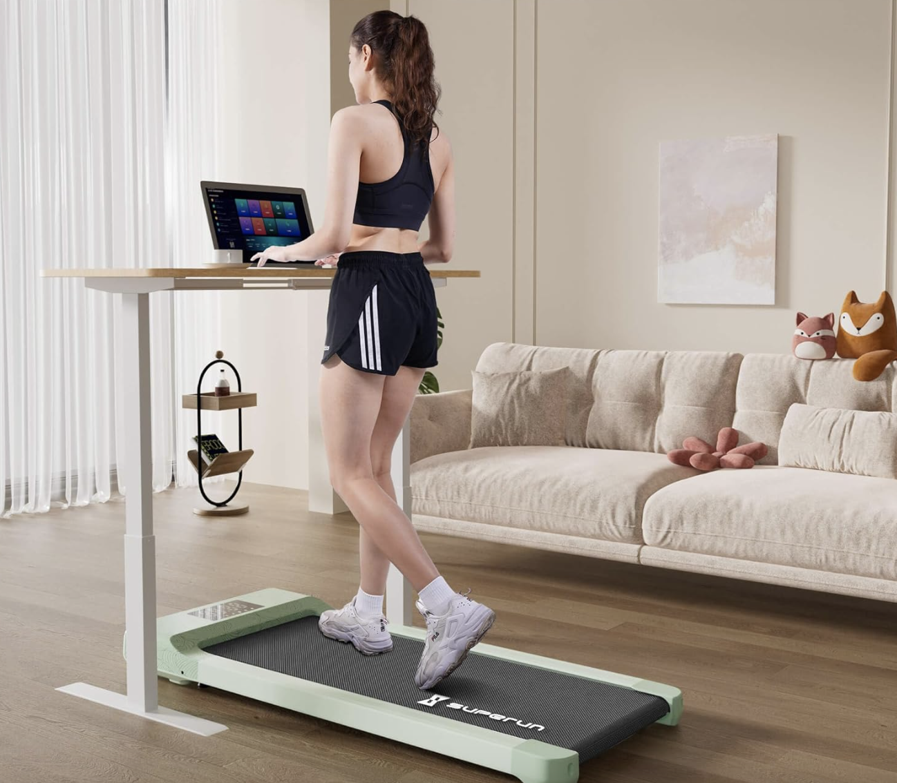 Woman walking on a compact treadmill at a standing desk setup in a home interior
