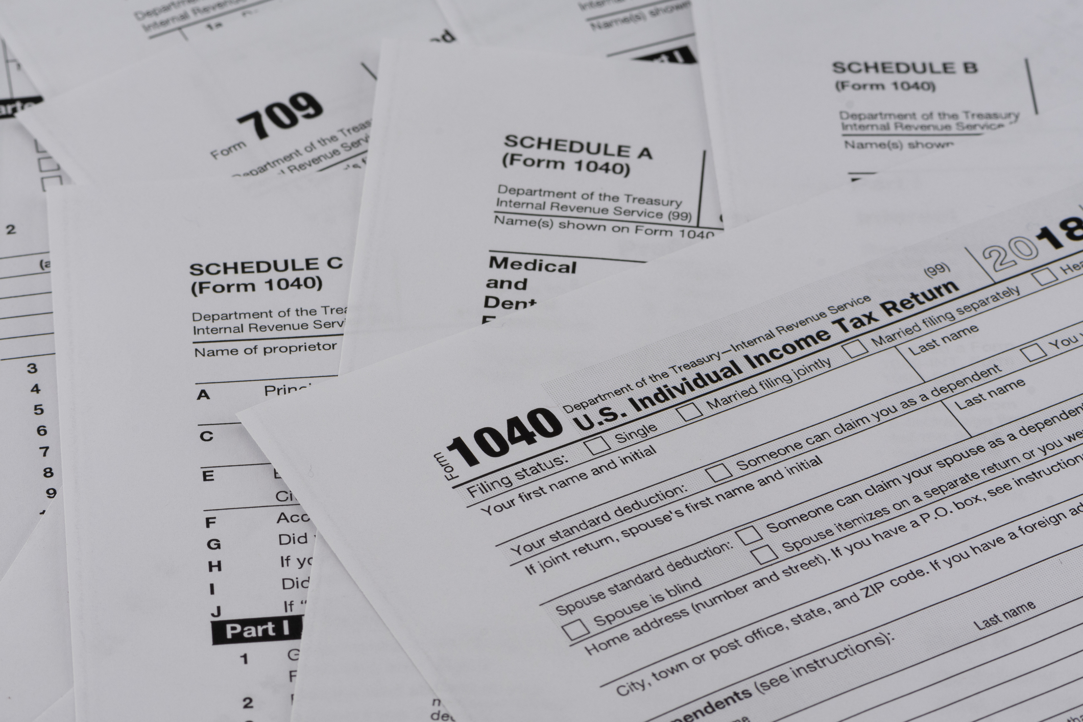 Assorted U.S. tax forms including the 1040 and Schedules A and B, indicating tax filing season