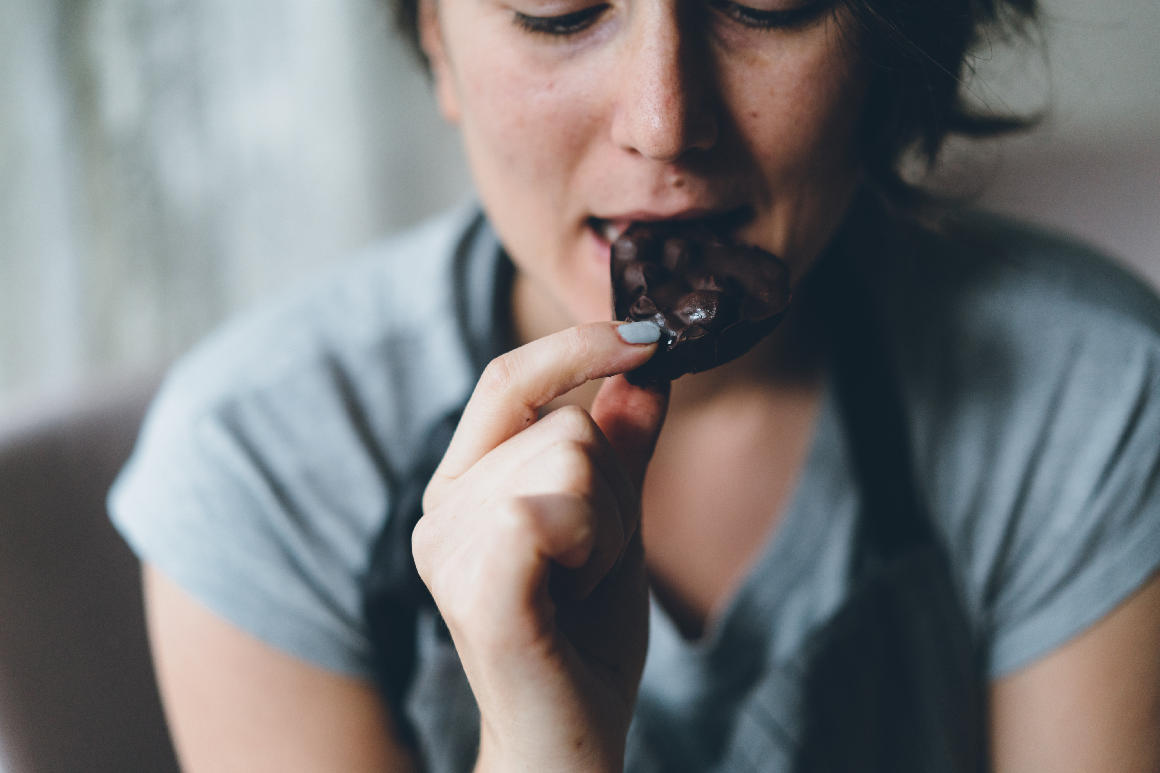 Person biting a piece of chocolate; emphasis on taste experience