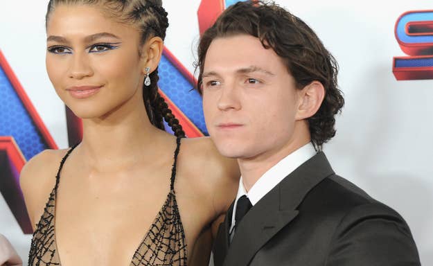 Zendaya in a detailed gown stands next to Tom Holland in a suit at a film premiere