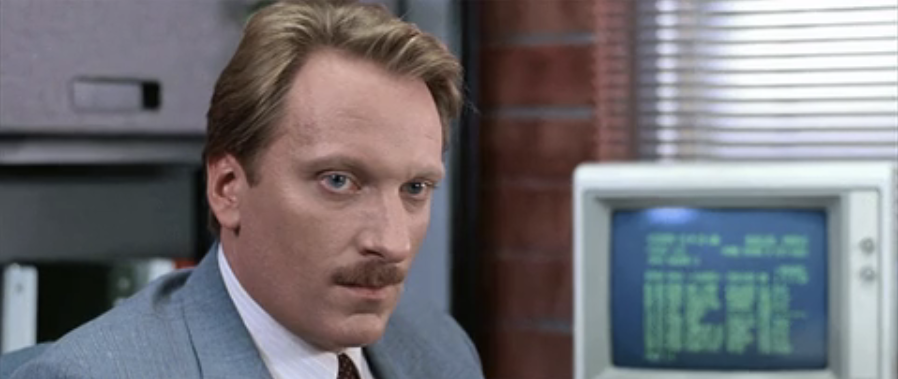 Man with mustache in office, old computer in background
