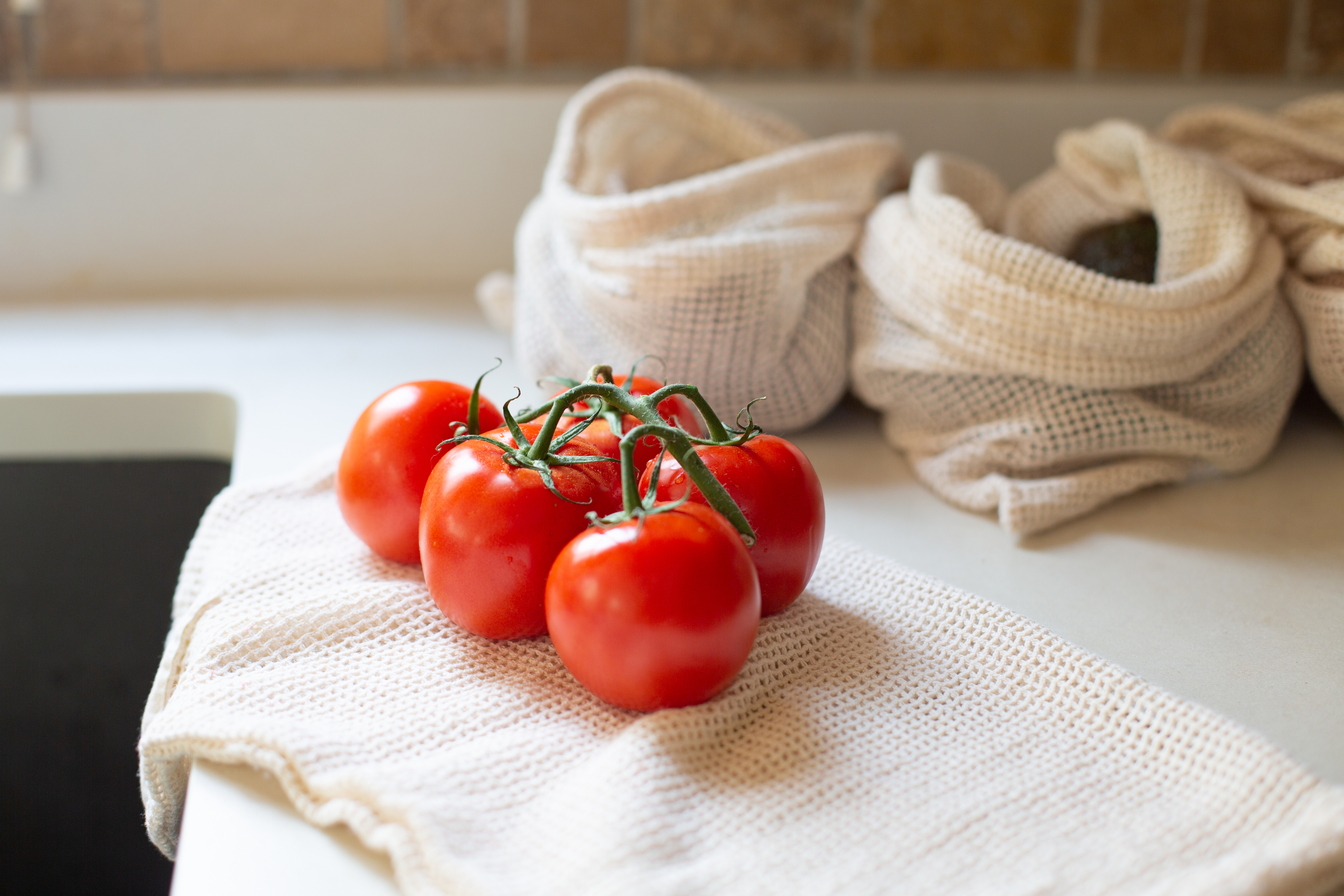 A cluster of ripe tomatoes on a kitchen counter with a white cloth