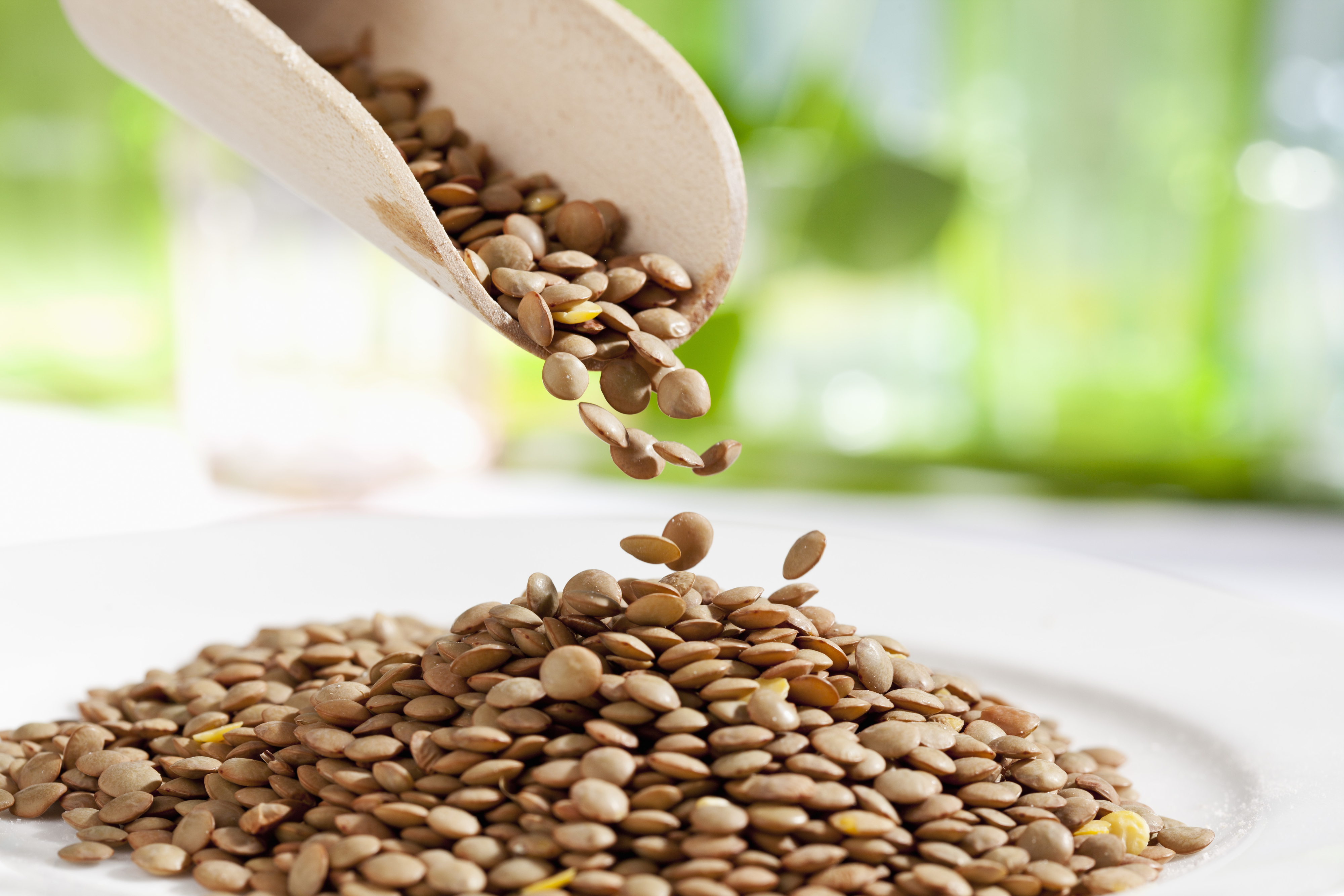 A scoop pouring lentils onto a surface, suggesting a focus on healthy eating or ingredients