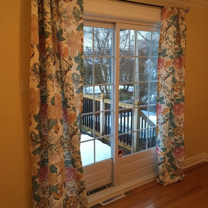 Floral patterned curtains framing a glass door leading to a balcony