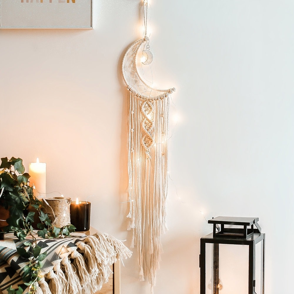 Wall-mounted moon macrame art piece with tassels, near a cozy home decor setup