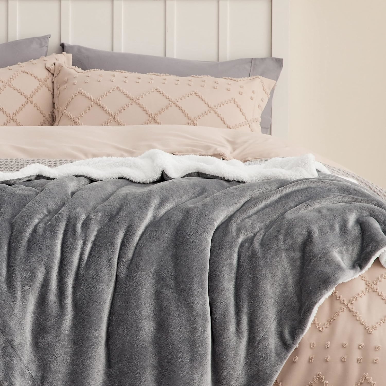 Plush gray blanket on a neatly made bed with decorative pillows