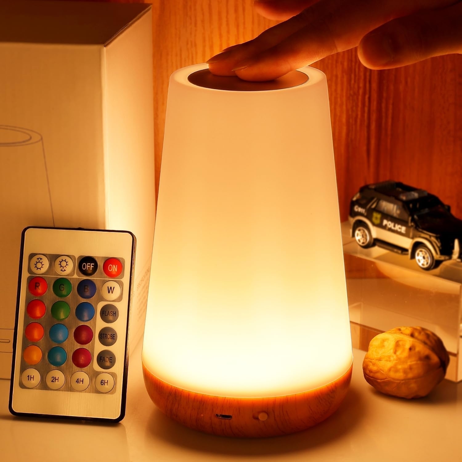 Hand touching a modern lamp with color control remote beside it, suitable for home ambience