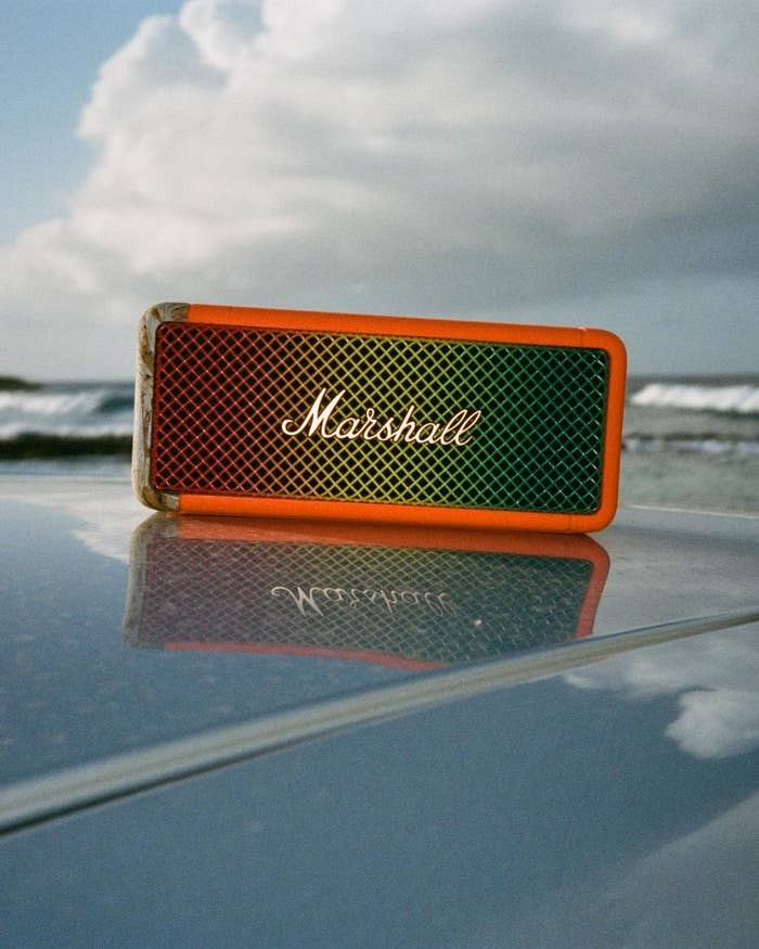 Marshall portable speaker on reflective surface with overcast sky and beach in background