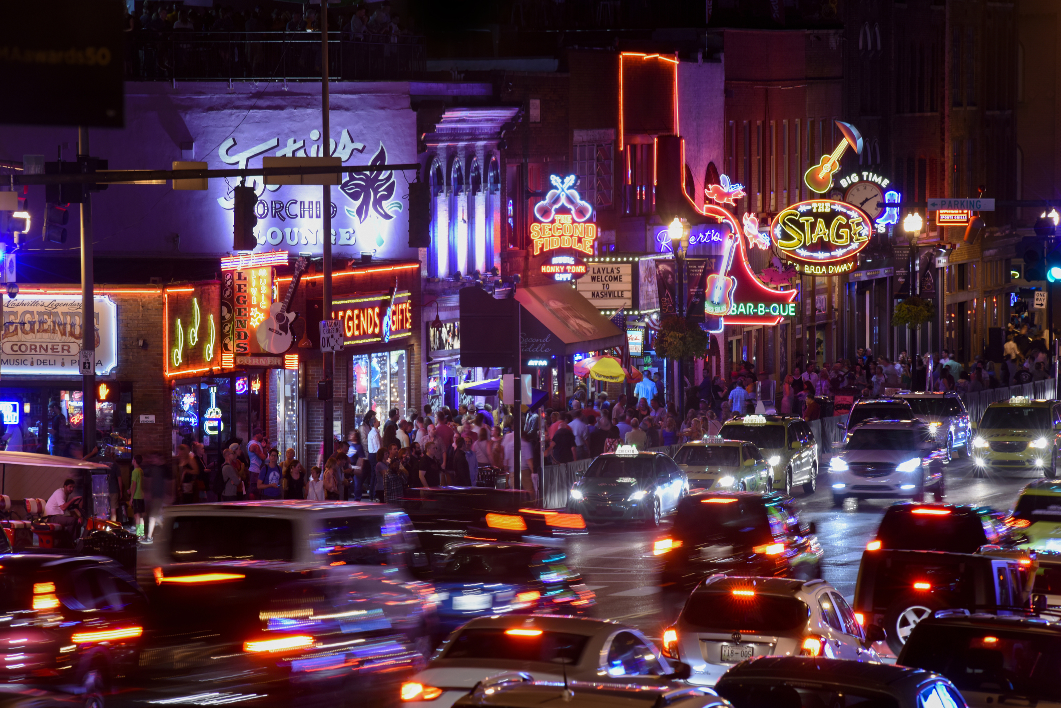 A busy street at night with neon signs and crowds in Nashville
