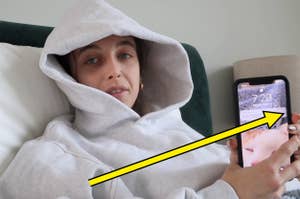 Emma Chamberlain holding up her phone with an arrow pointing to it