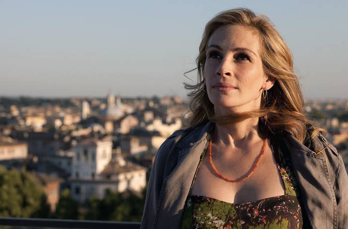 Julia Roberts in a jacket over a floral top looking away against a cityscape background