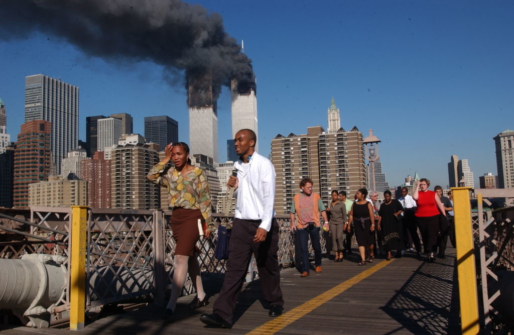 People evacuate as smoke billows from Twin Towers in the background during 9/11 attacks