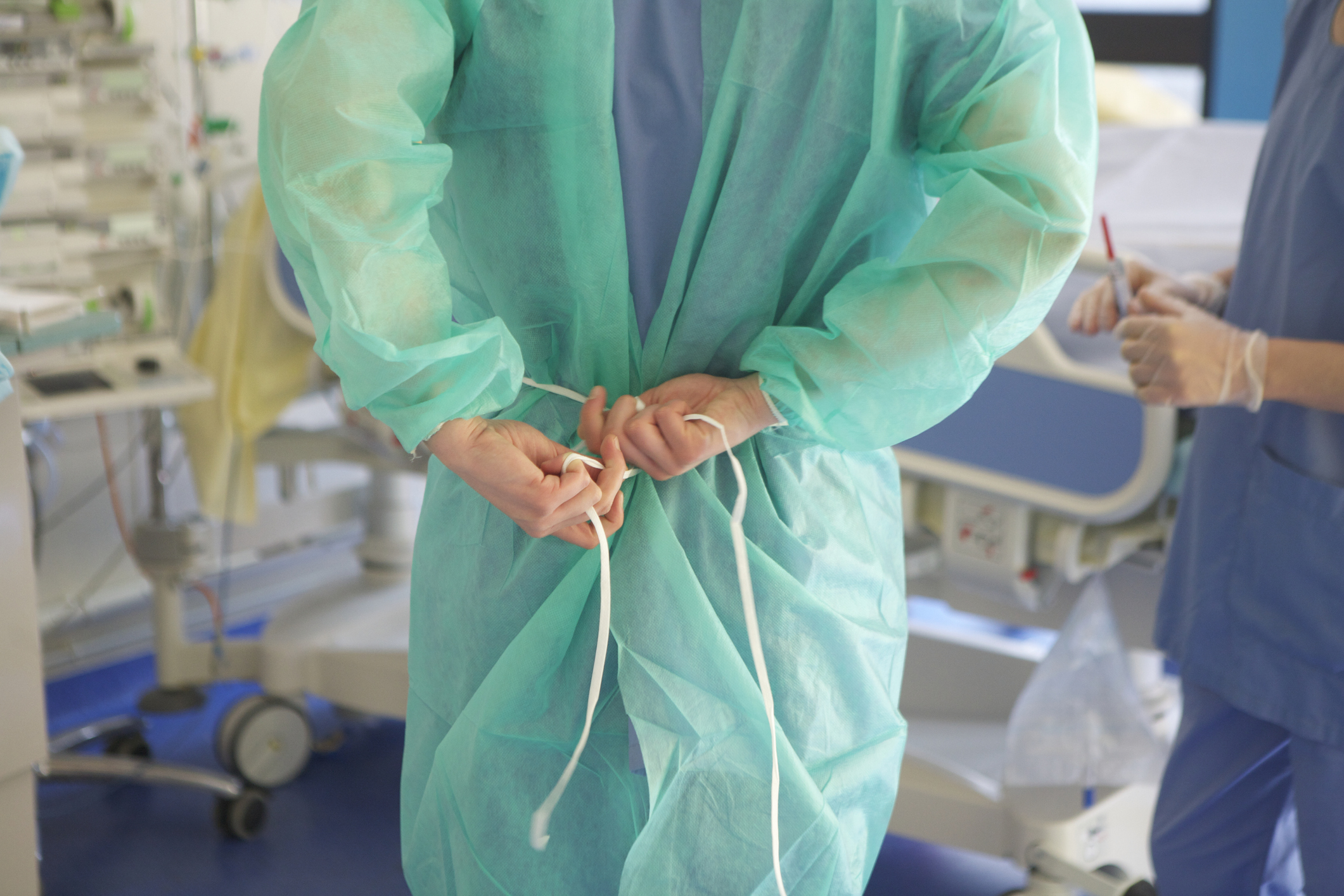 Person tying the back of a surgical gown in a hospital setting