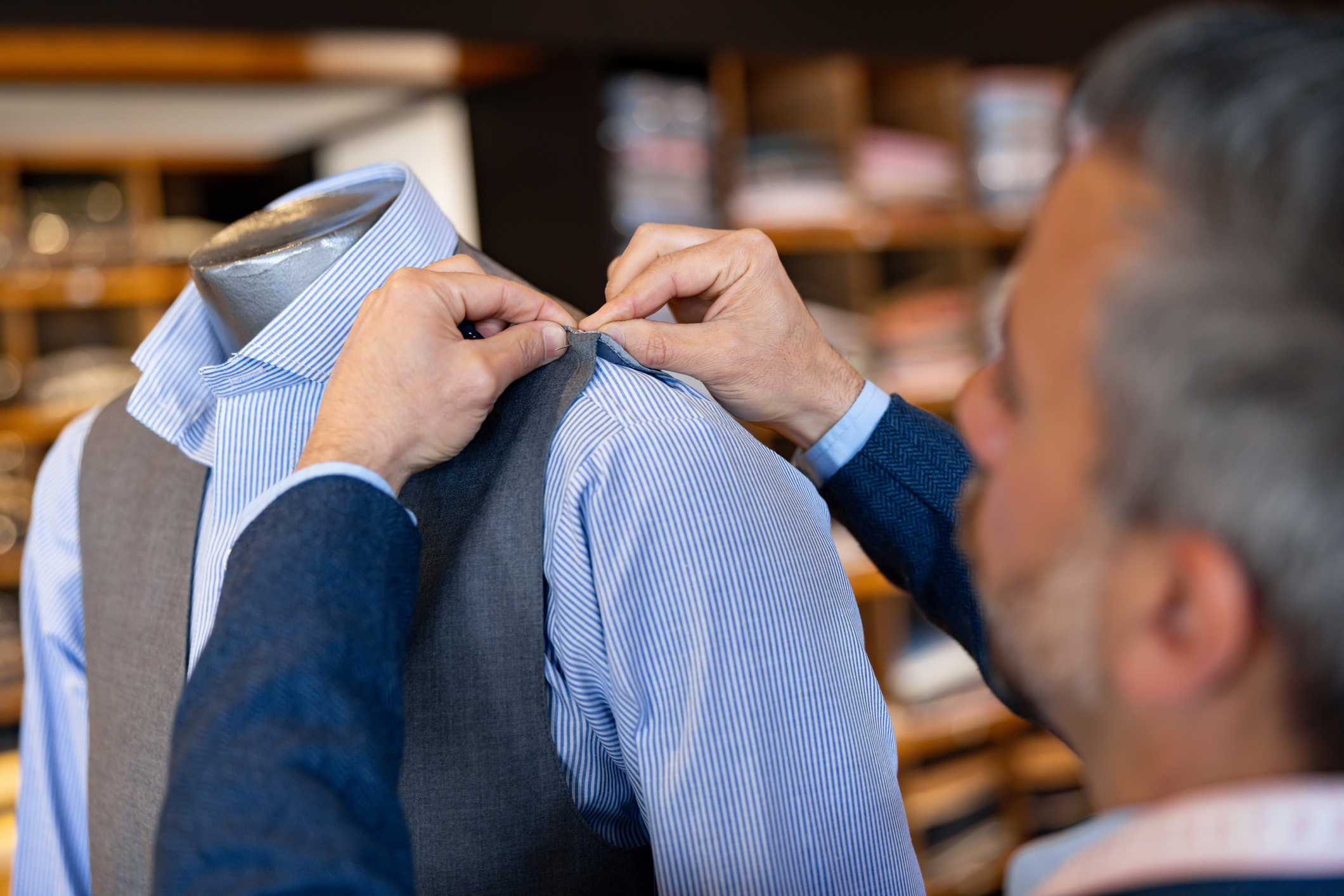Tailor adjusting a mannequin&#x27;s striped shirt collar