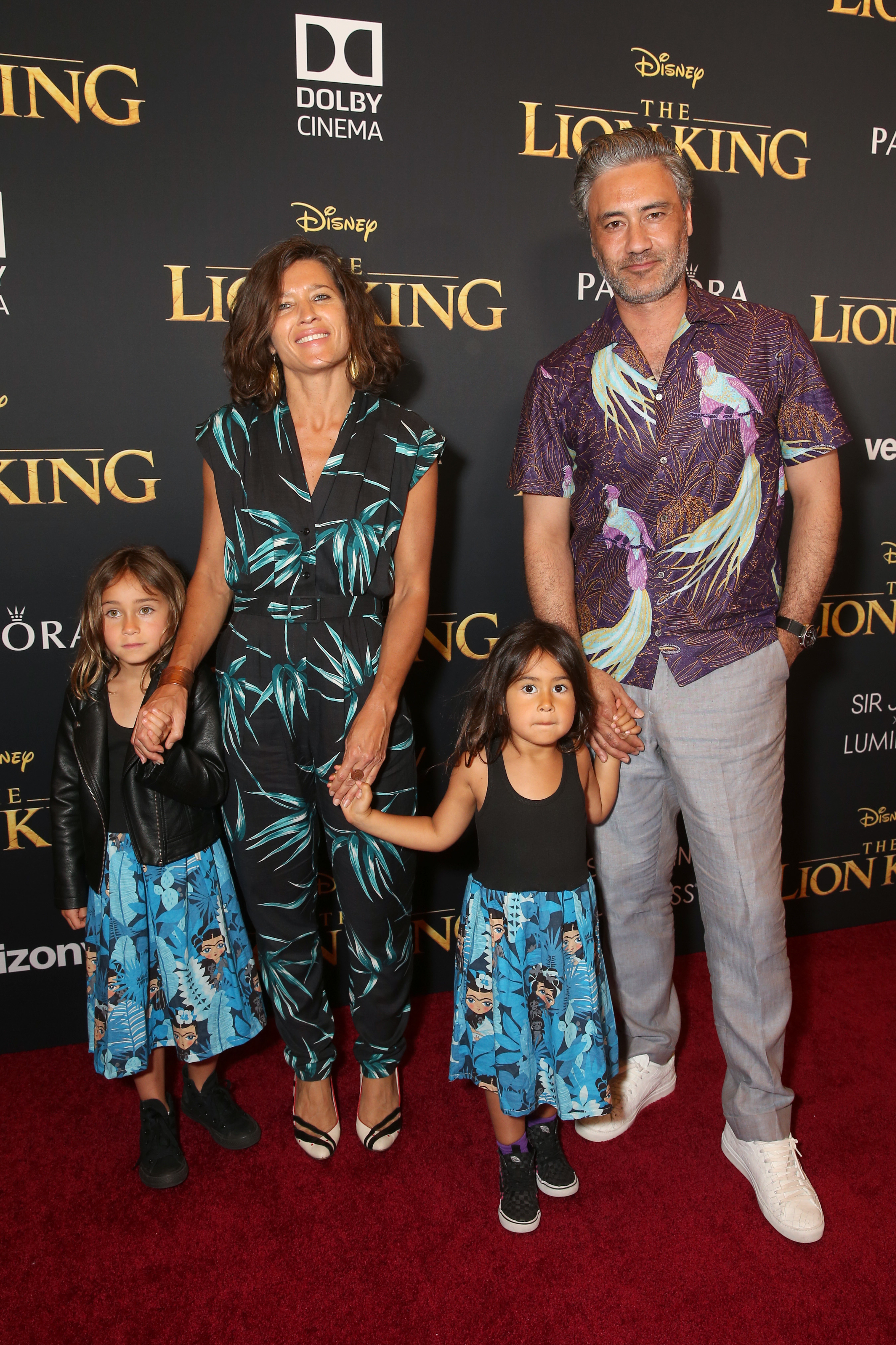 Taika, Chelsea, and their two children at The Lion King premiere, all wearing outfits with Polynesian-inspired prints