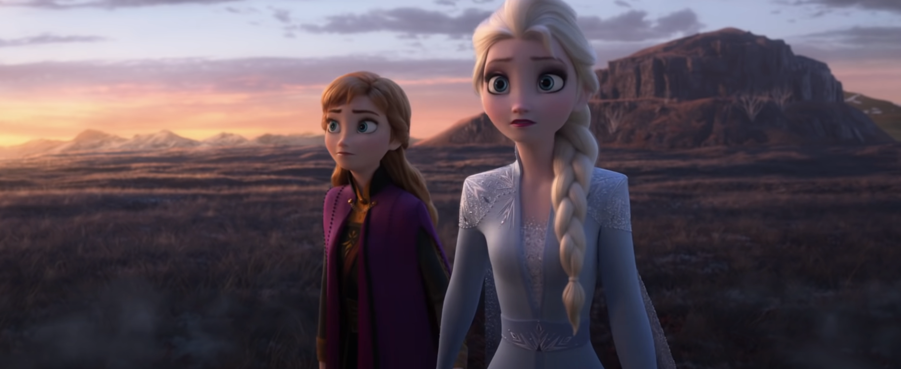 Anna and Elsa from Frozen stand side by side with a worried look, gazing into the distance