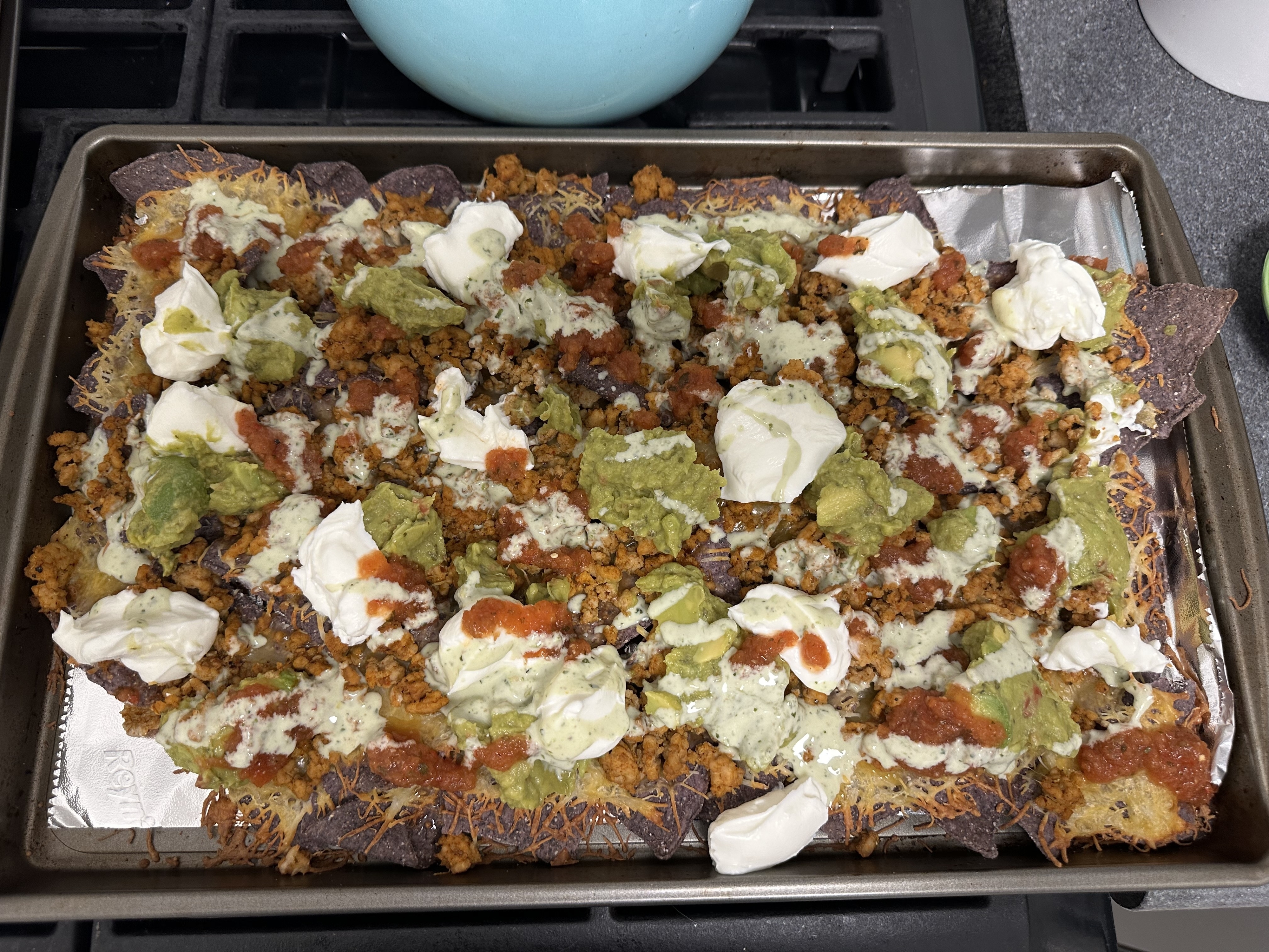 Tray of nachos loaded with various toppings like cheese, dollops of sour cream, and guacamole