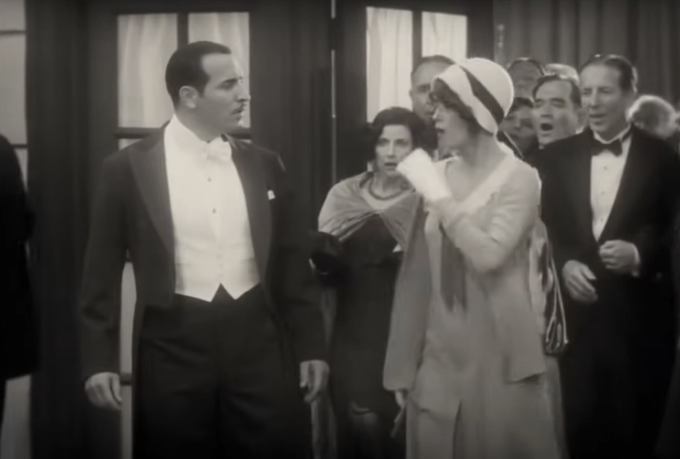 Scene from The Artist featuring actors in 1920s formal attire; man in a tuxedo and woman in a flapper dress with a headband