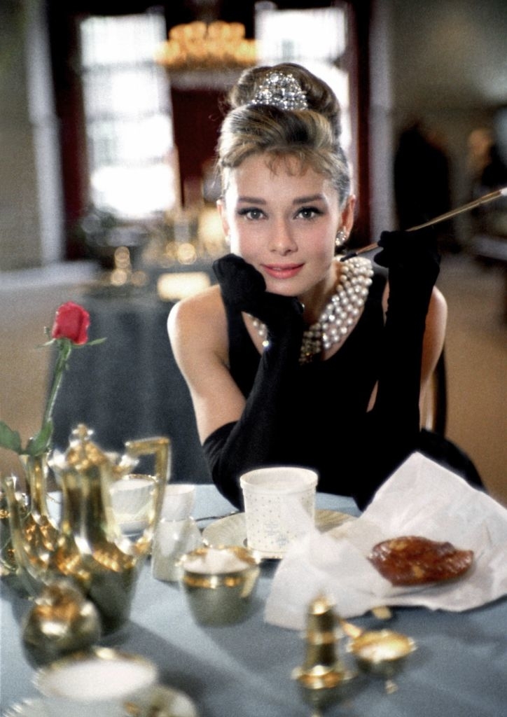 Audrey Hepburn in &quot;Breakfast at Tiffany&#x27;s&quot;, wearing a black dress, tiara, and gloves, with a cigarette holder
