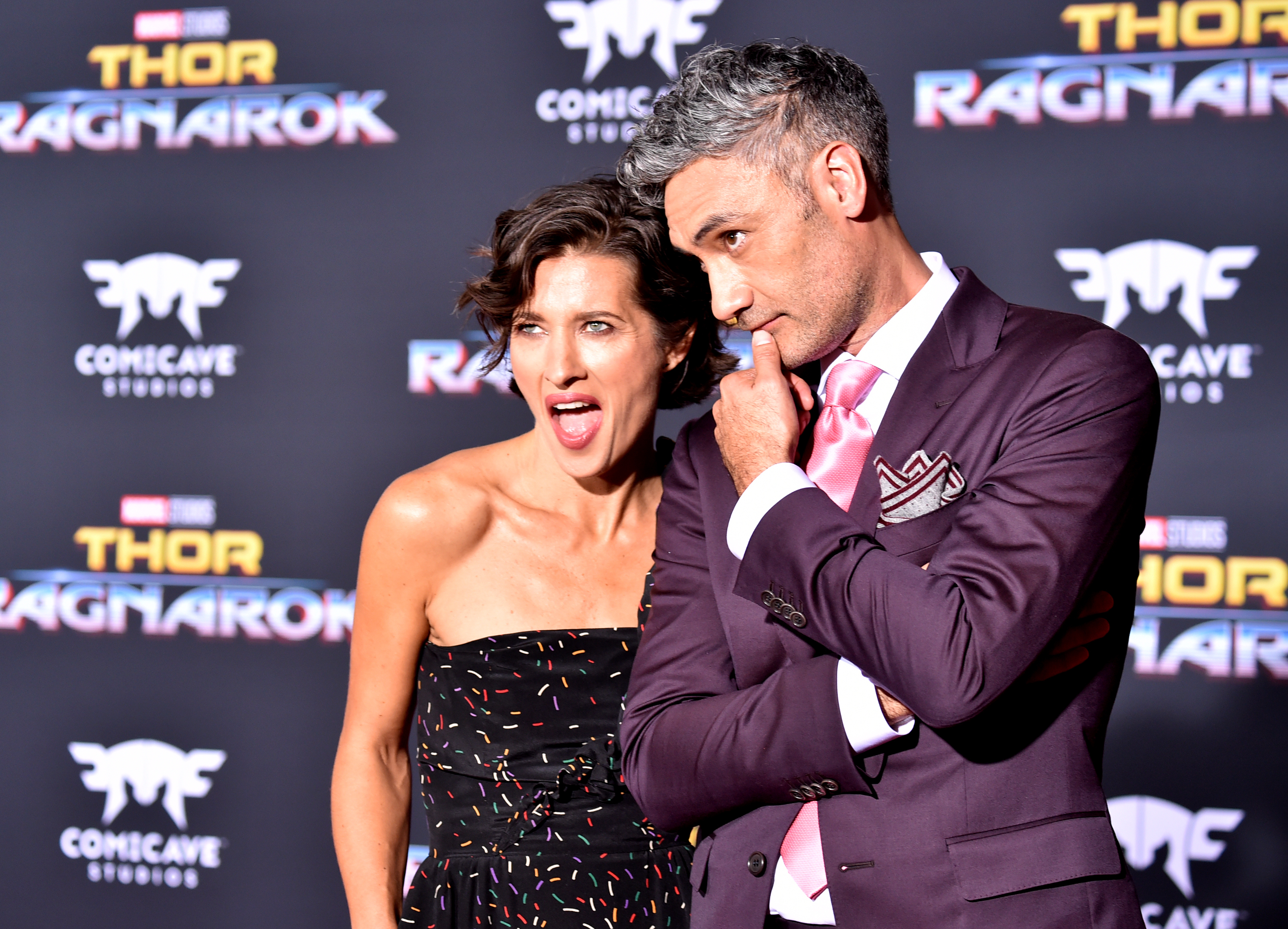 Chelsea, in a strapless outfit, and Taika, in a suit and tie, at a Thor: Ragnarok event