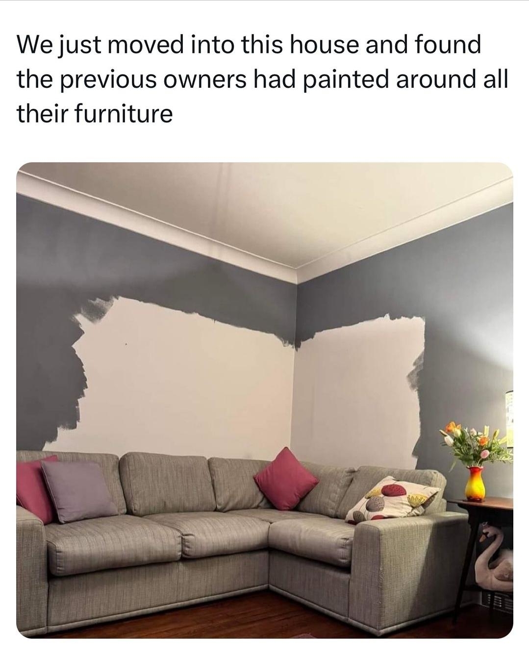 A sofa with uneven paint on walls behind it, where previous owners painted around decor, leaving patches
