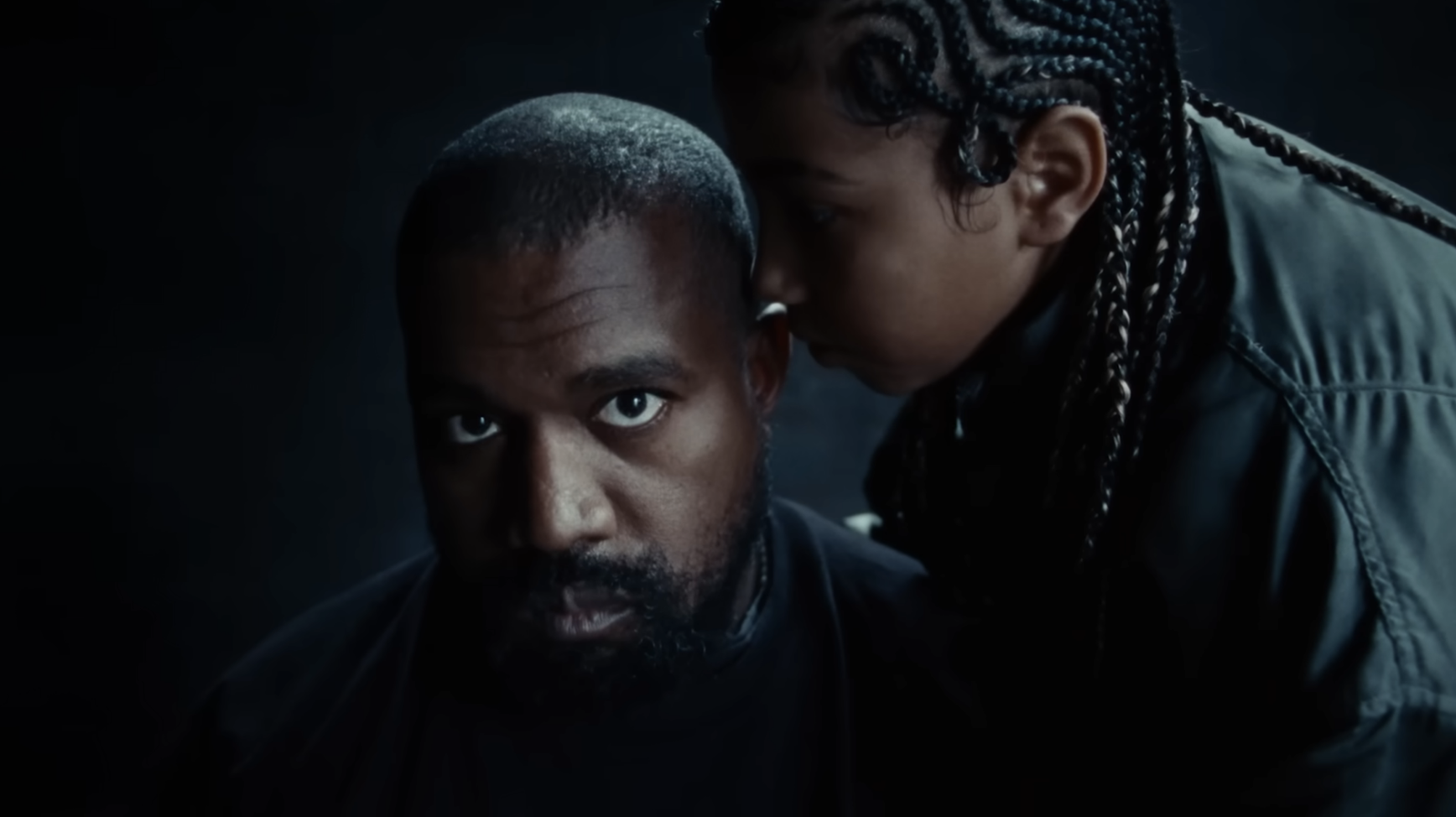 Kanye West and daughter, close up, serious expressions, dark backdrop