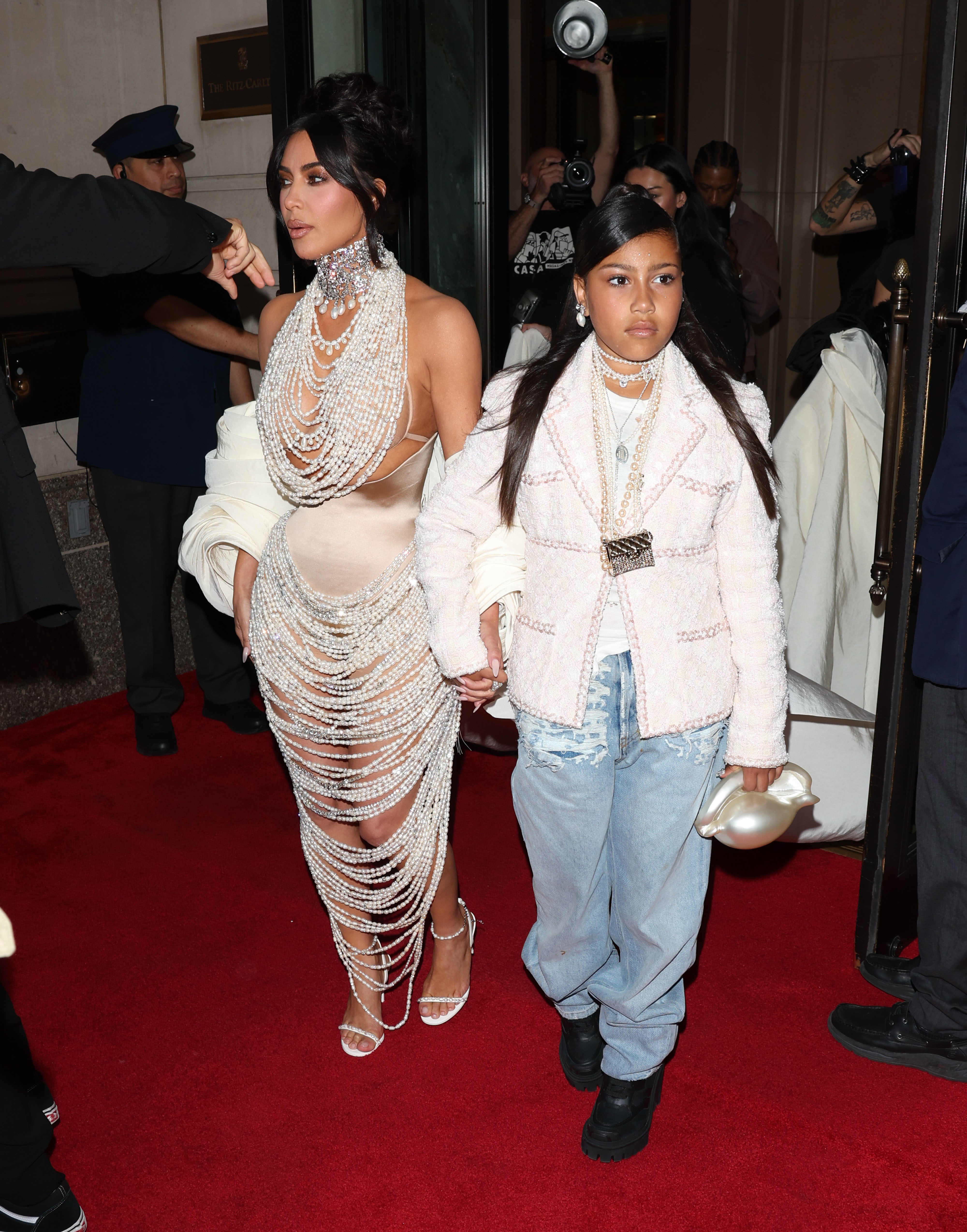 Kim Kardashian in a crystal-adorned sheer gown poses with North West, who is dressed in a pink jacket and jeans