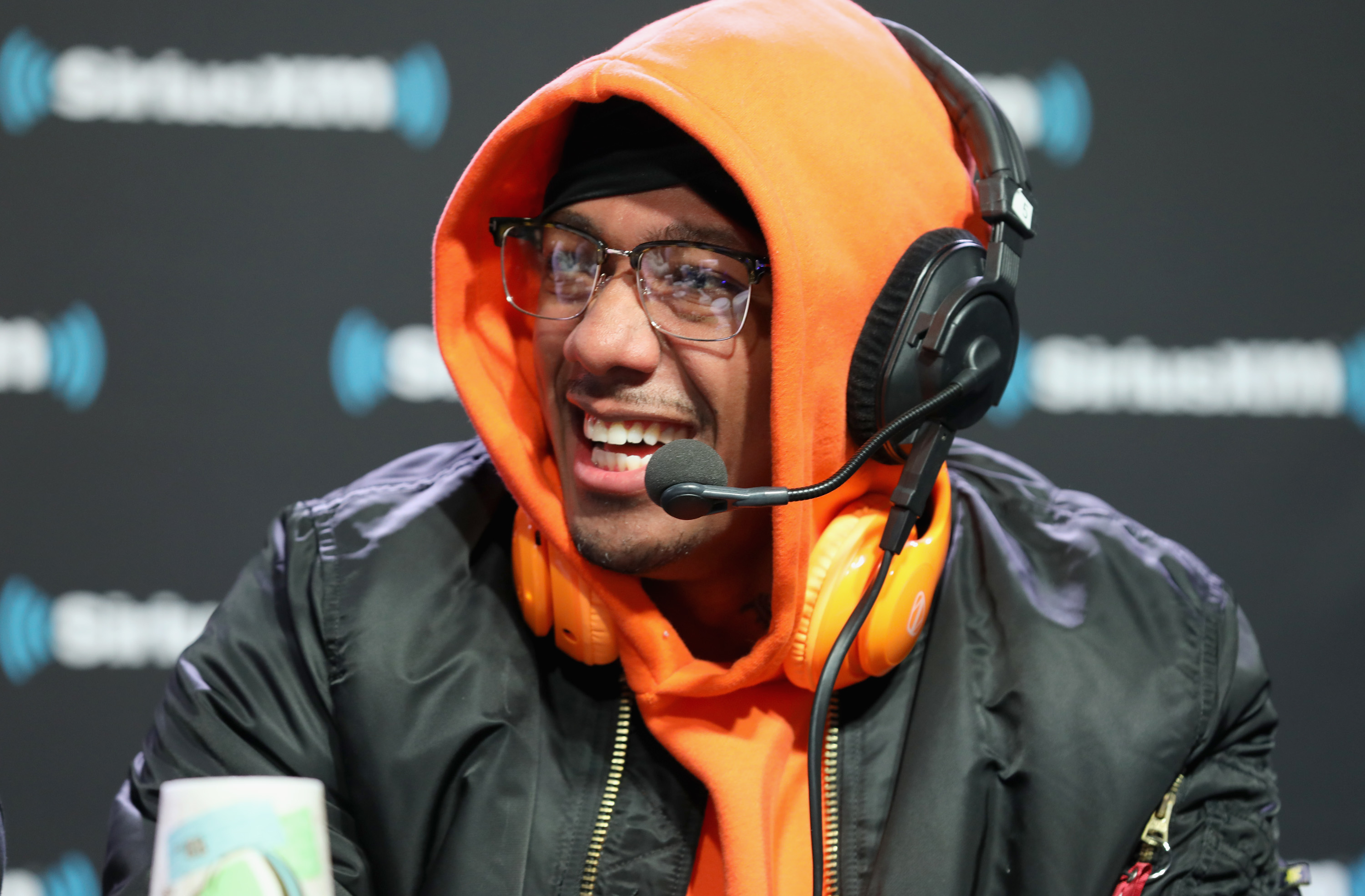 Man in orange hoodie and headphones smiling during a podcast recording session