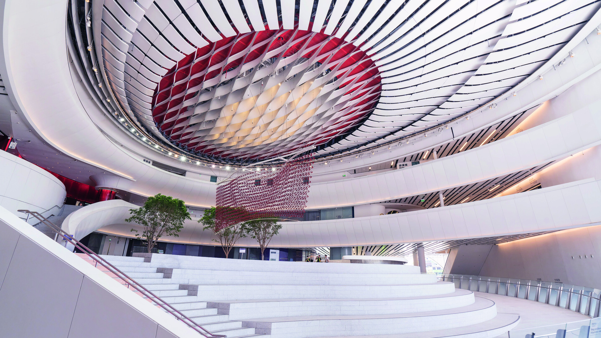 Curved architectural design of a building&#x27;s interior with sweeping staircases and an intricate ceiling
