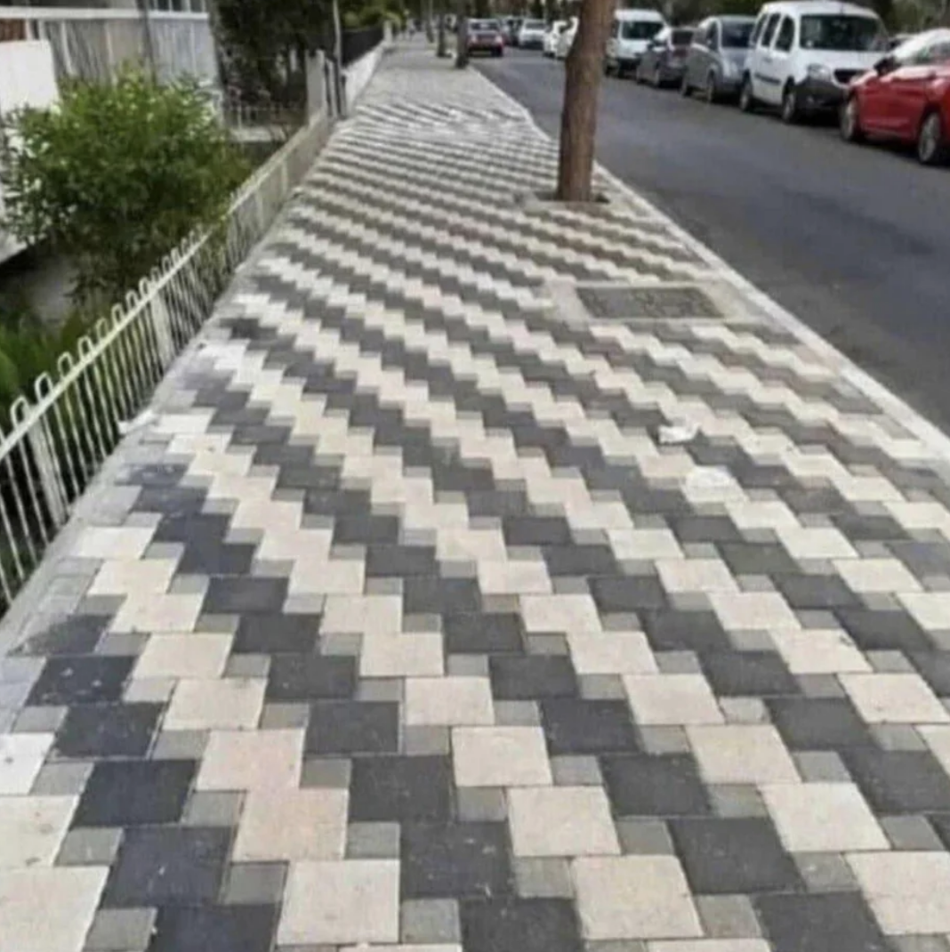 Sidewalk with an optical illusion of a wavy pattern created by contrasting paving stones