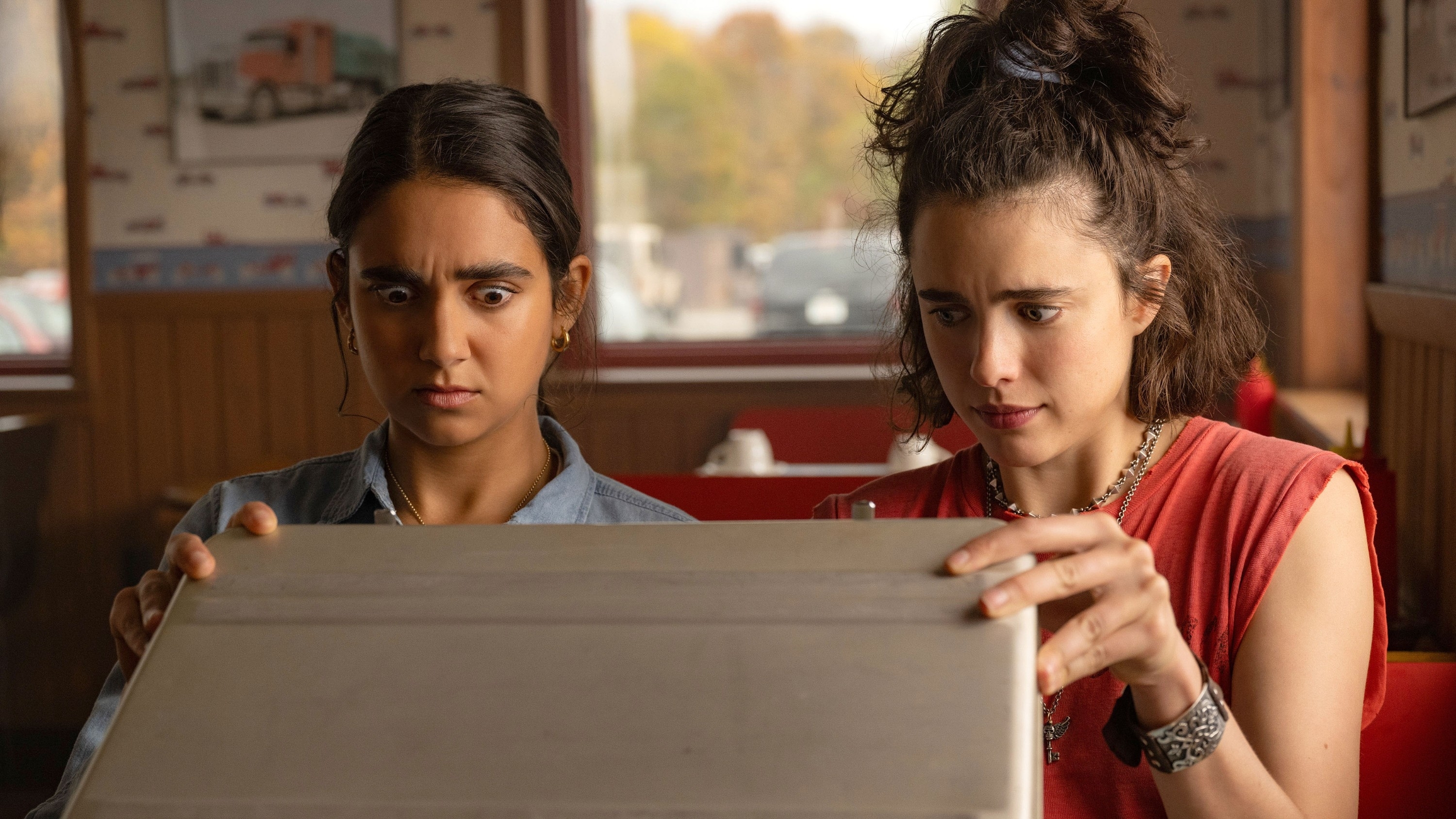 Jamie and Marian looking into a briefcase with concern in a scene from &quot;Drive-Away Dolls&quot;