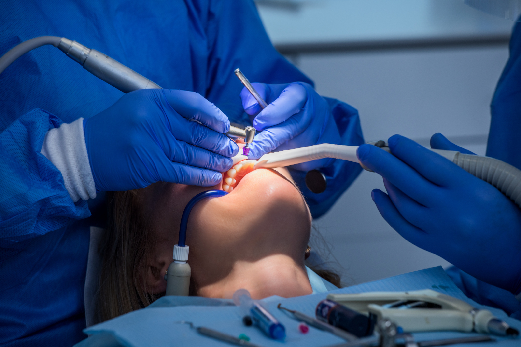 Dentist performing a procedure on a patient with dental tools and overhead light