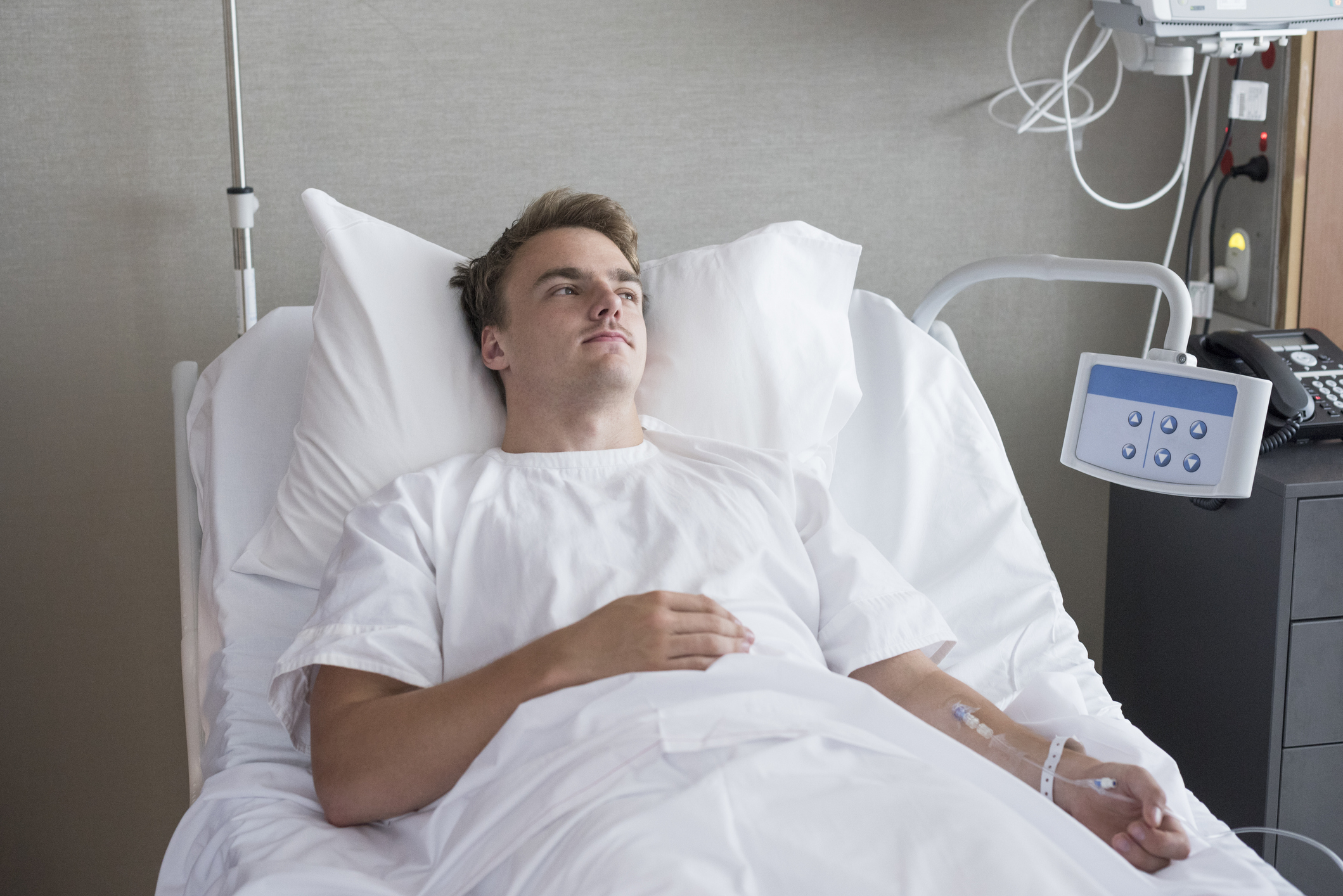 Person in a hospital bed with medical equipment in the background