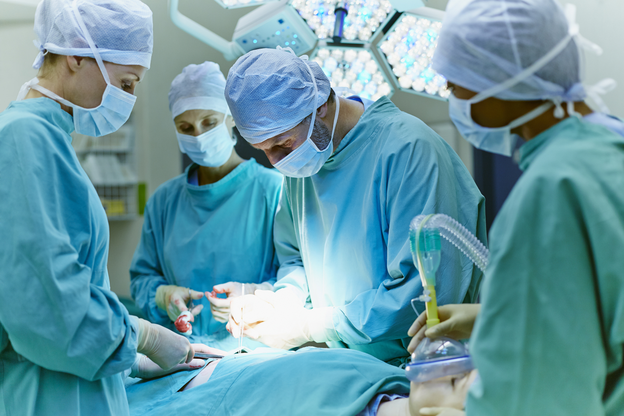 Surgeons in scrubs performing an operation in a well-lit operating room