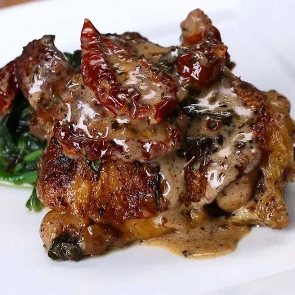 Grilled chicken topped with sun-dried tomatoes and greens on a plate