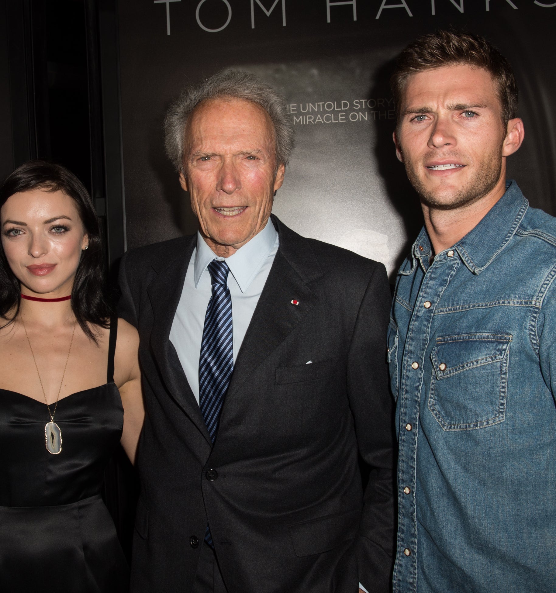 father and son  pose at a premiere; Clint in a suit flanked by Scott in denim