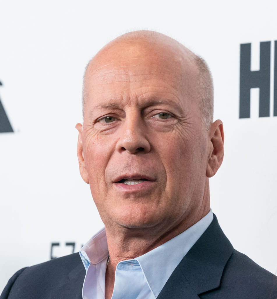 Bruce Willis wearing a navy suit and light shirt at a film premiere