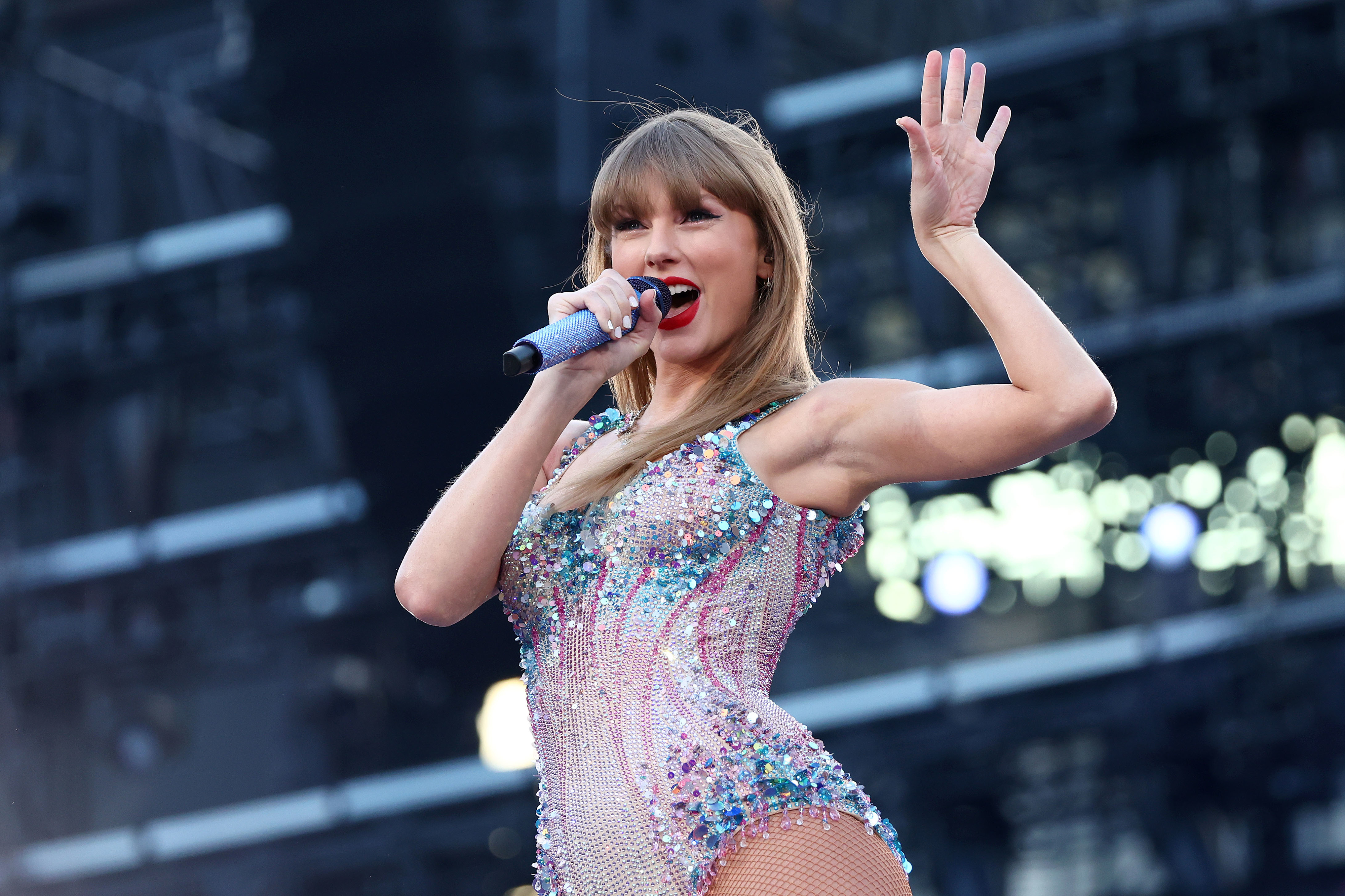 Taylor Swift in sparkling bodysuit singing on stage with microphone in hand