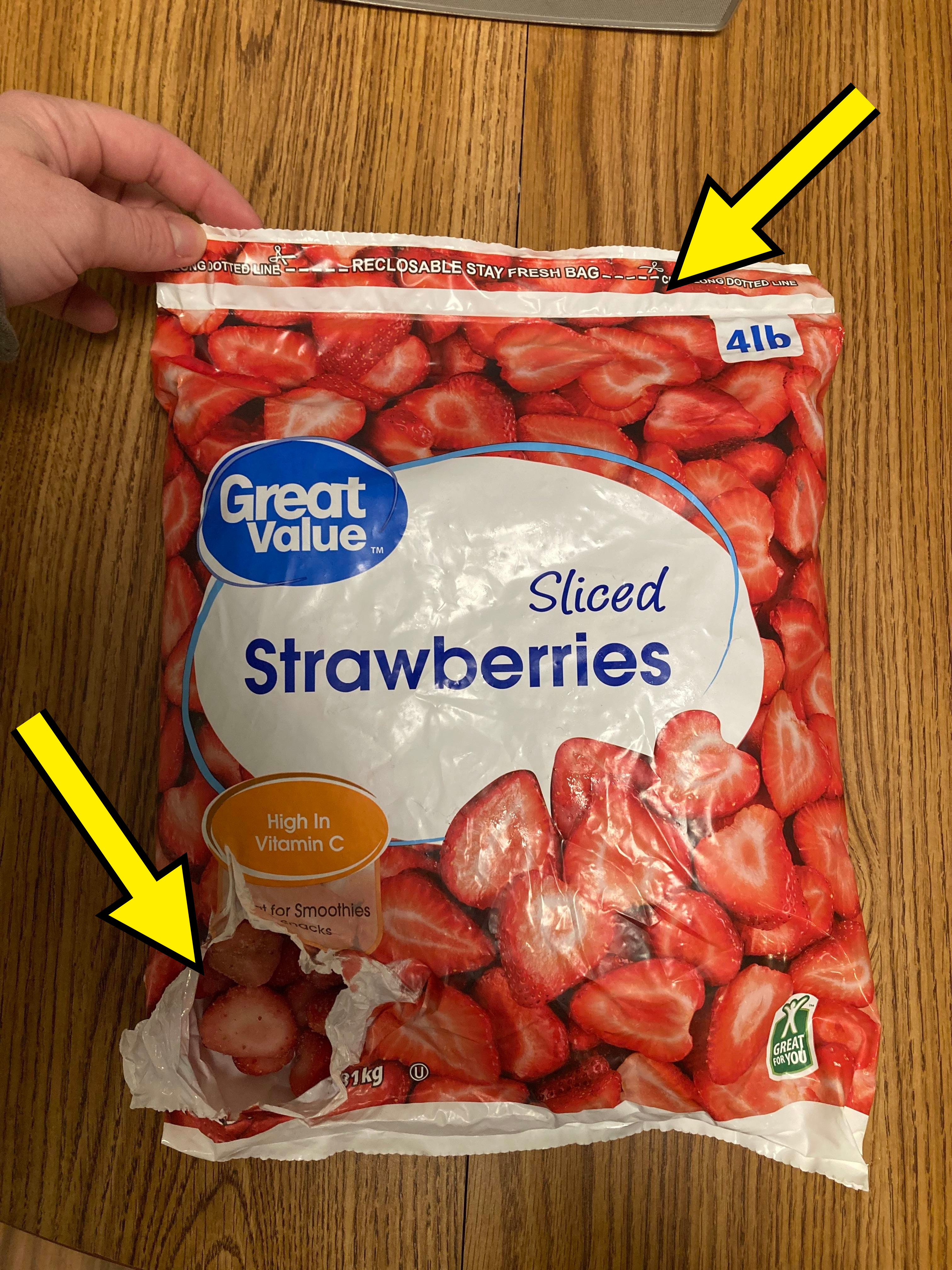A hand holding a Great Value brand bag of sliced strawberries. Text highlights &#x27;High in Vitamin C&#x27; and &#x27;for Smoothies.&#x27;