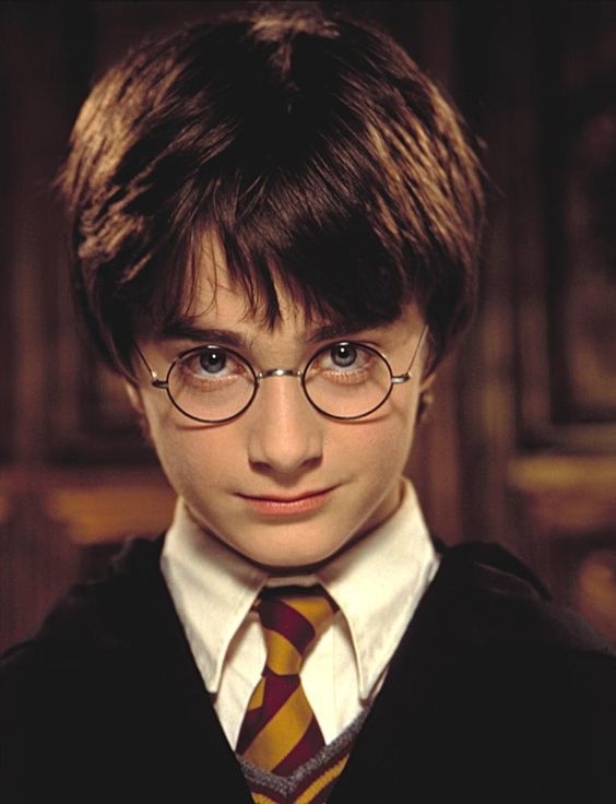 Primer plano de Harry Potter con gafas redondas y uniforme de Hogwarts con corbata a rayas