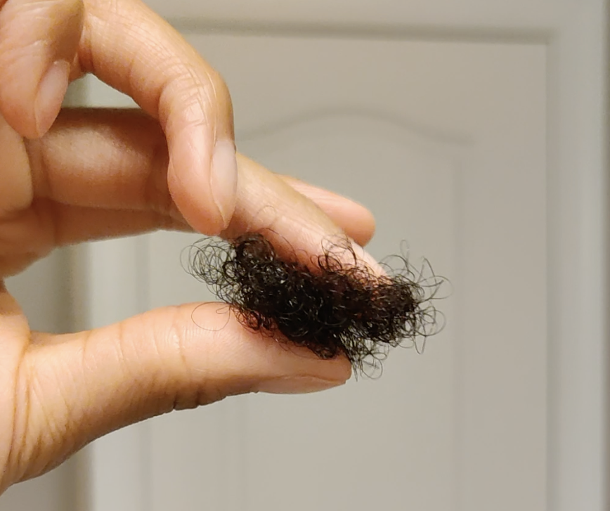 A person holding a clump of hair between their fingers