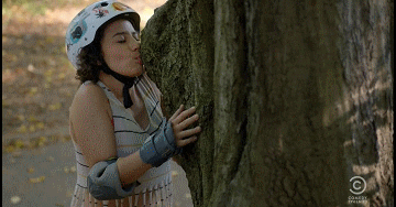 Person in helmet affectionately hugging and kissing a tree
