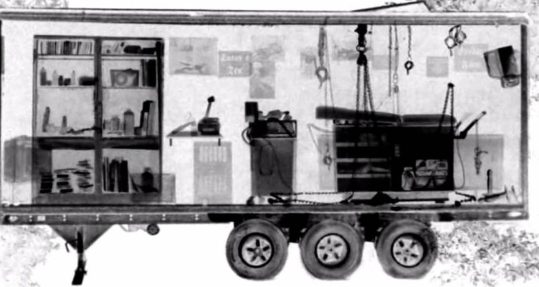 An X-ray of a trailer showing objects inside: shelves with items, equipment, and a wheelchair hanging