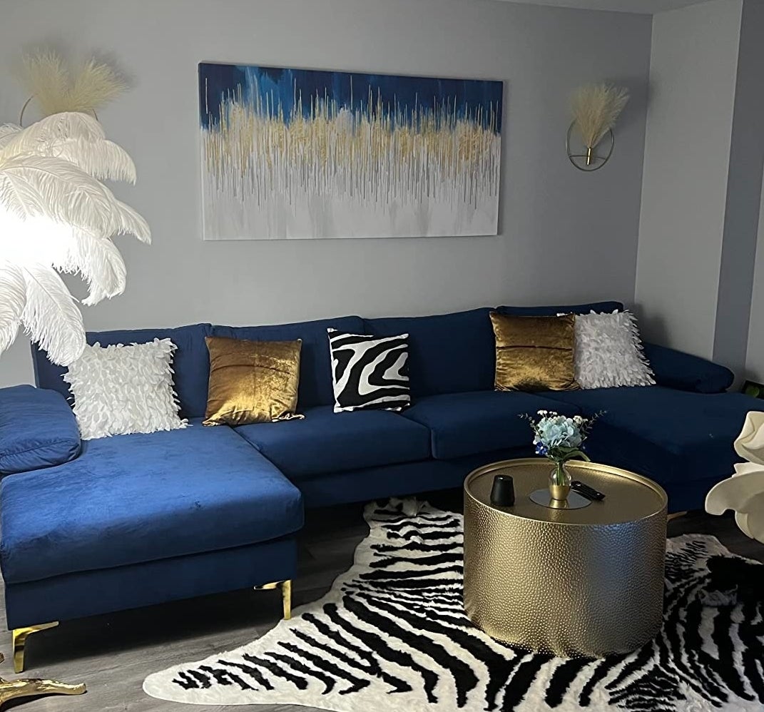Living room with blue sectional sofa, zebra rug, gold accents, and wall art