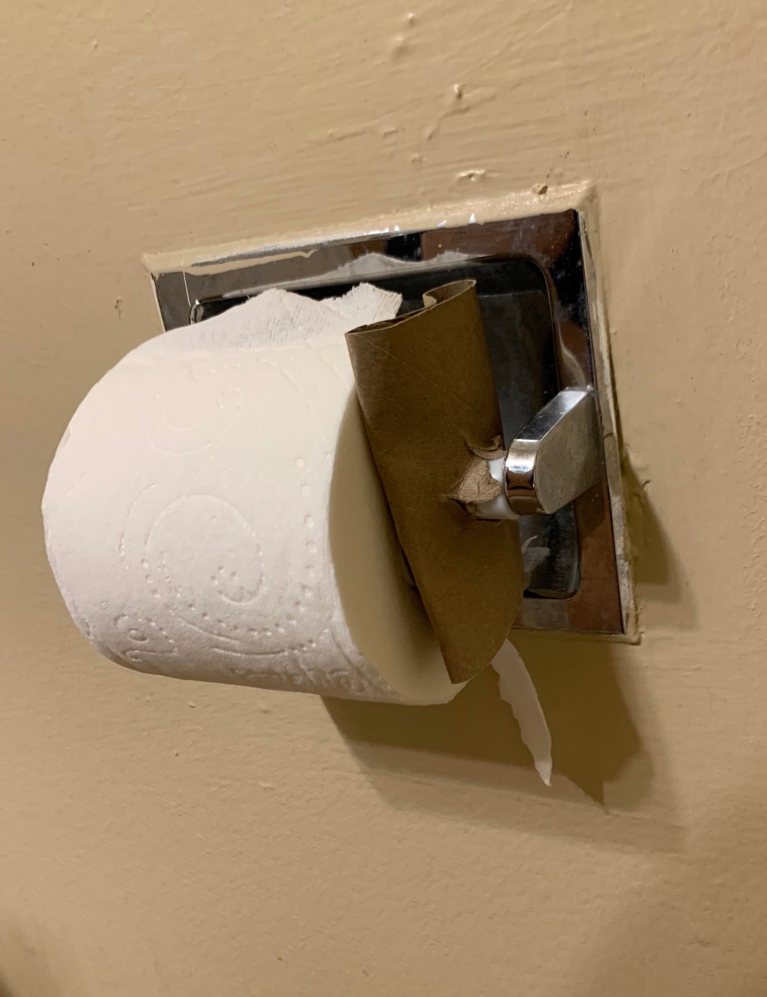 Toilet paper roll incorrectly placed with paper end against the wall