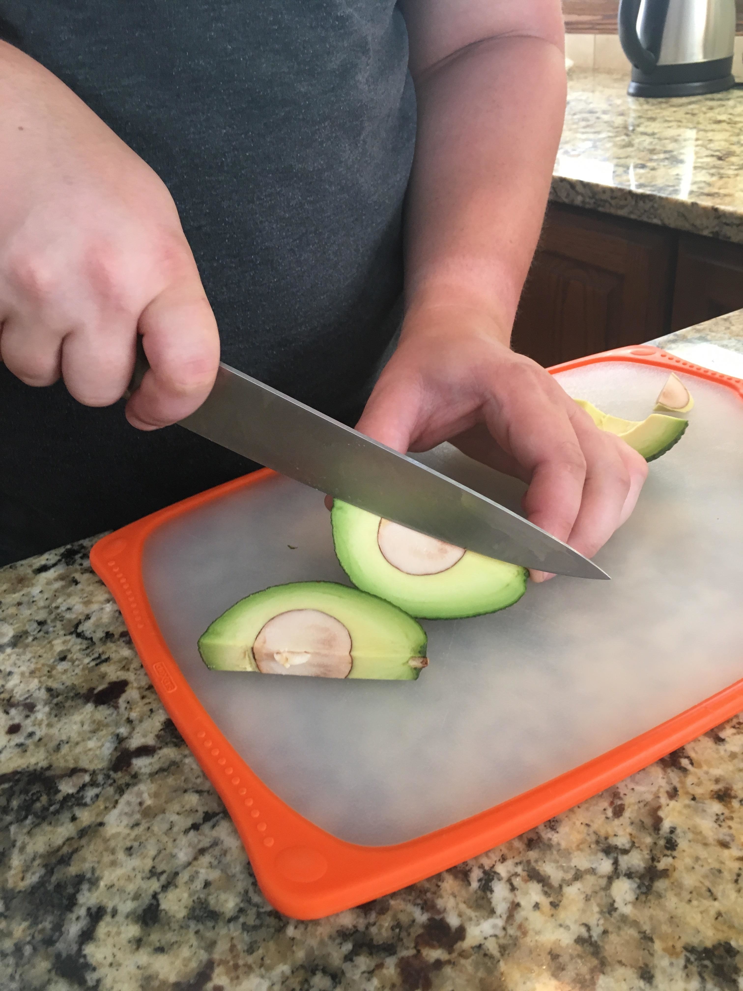 Person slicing an avocado on a cutting board